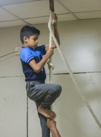Gymnastic boy climbing rope
